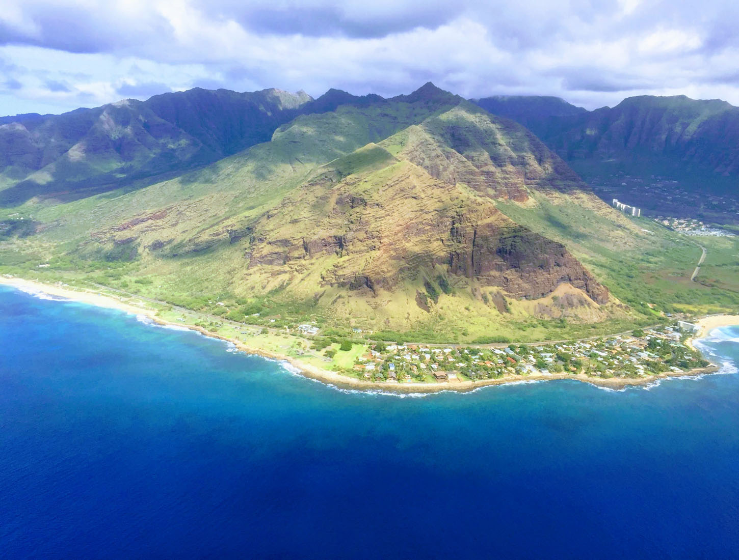 Aerial view of green mountains and a coastline facing the blue ocean