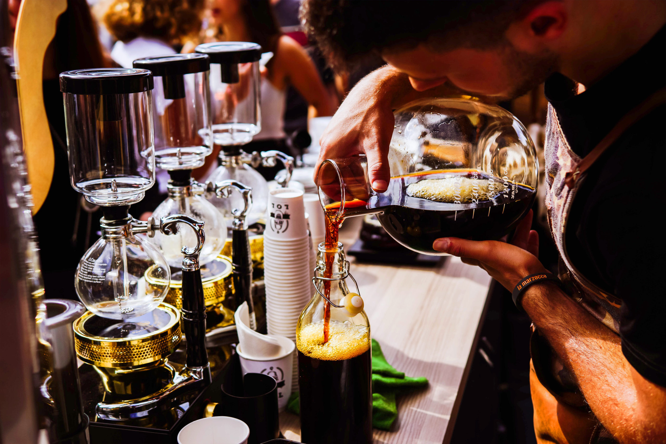 サイフォンの並ぶカウンターで、淹れたコーヒーを瓶に注ぐ様子