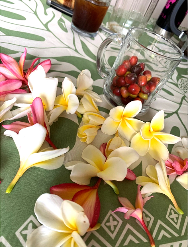 テーブルに撒かれたプルメリアの花と、赤いコーヒーチェリーを入れたガラスの器