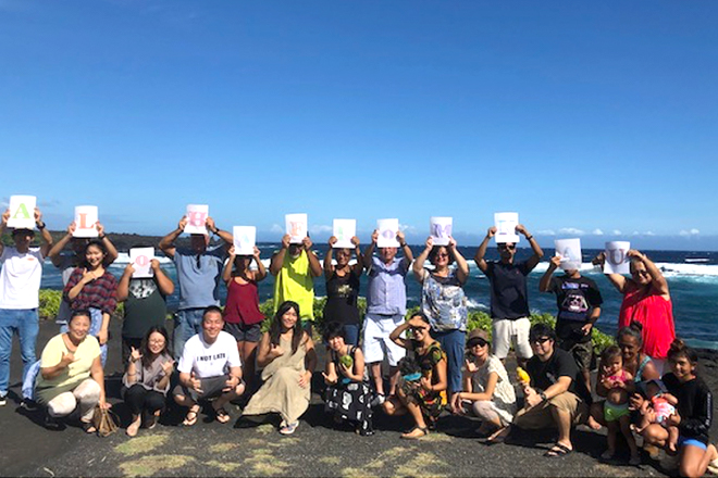 海を背にして「Aloha from Ka'u」の文字を掲げる参加者たち